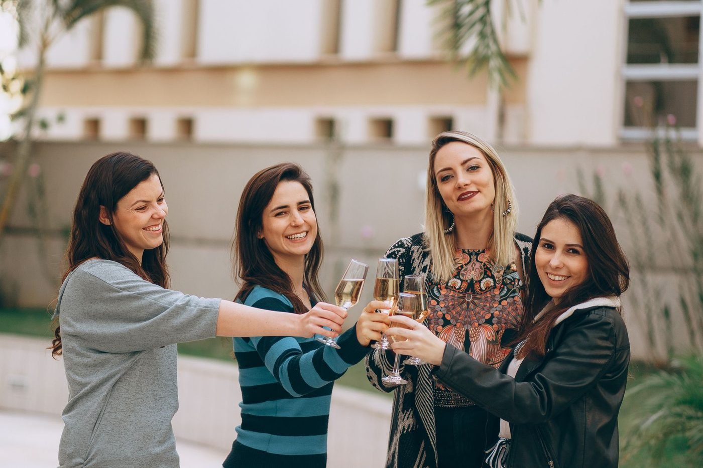 Quatre amies trinquent au champagne en extérieur pendant un EVJF